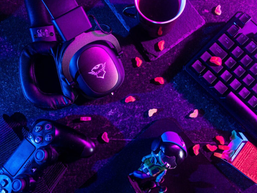 pexels-photo-3165335 Colorful flat lay of gaming gear including headset, controller, and keyboard under vibrant lighting.